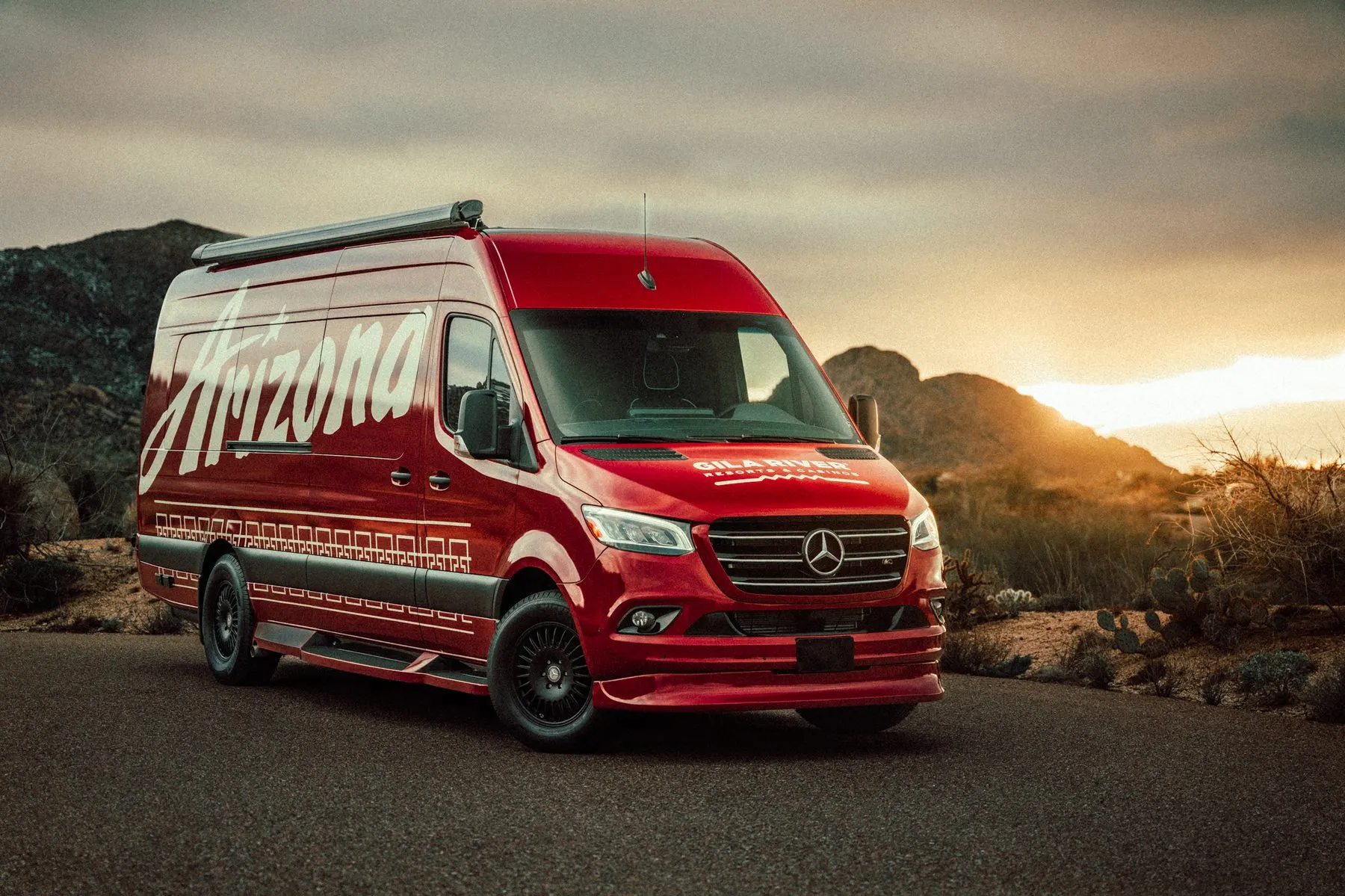 Custom wrapped van, front three quarter at sunrise, the mark across the hood