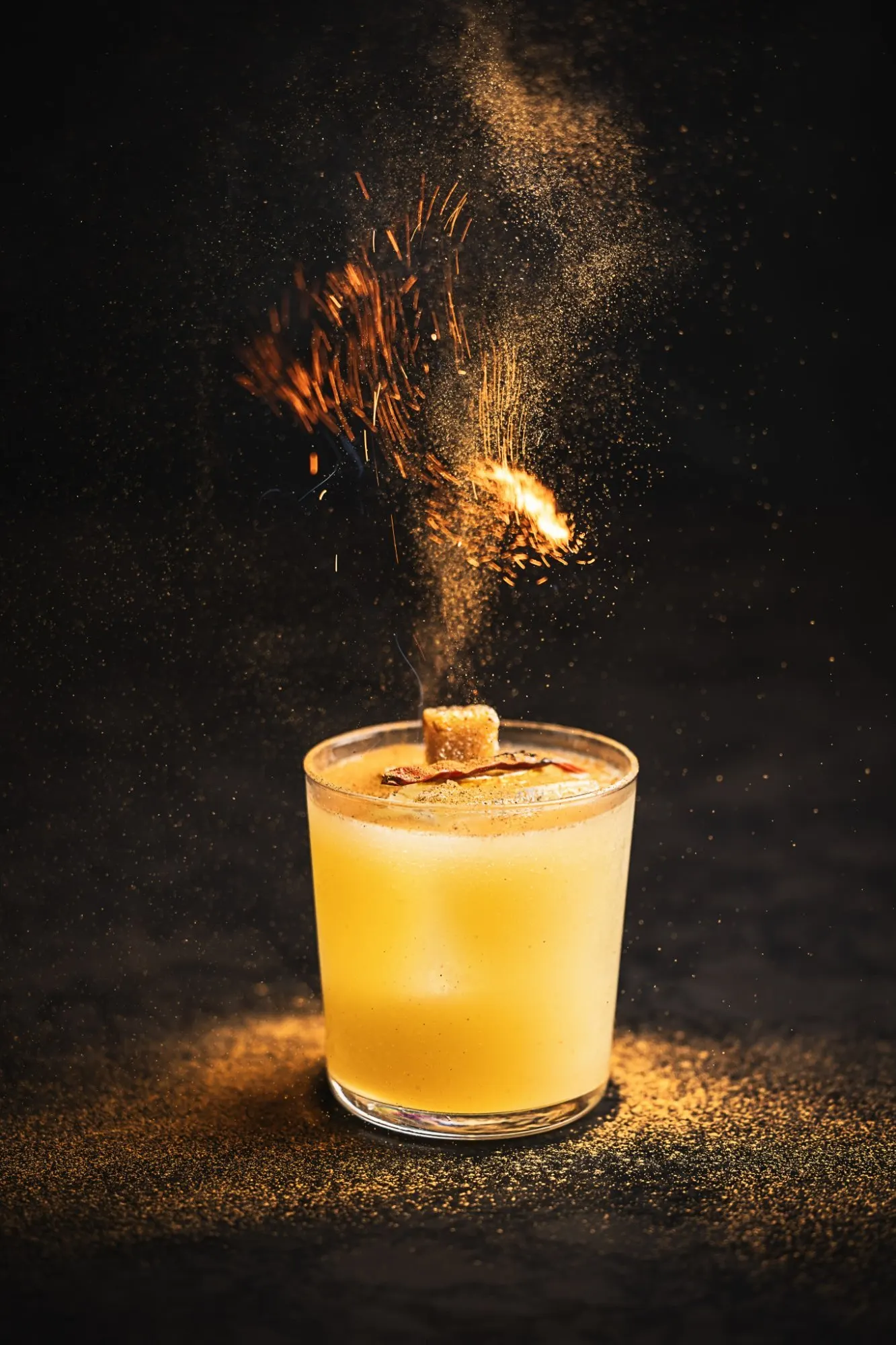 Cocktail with lit garnish and falling spice