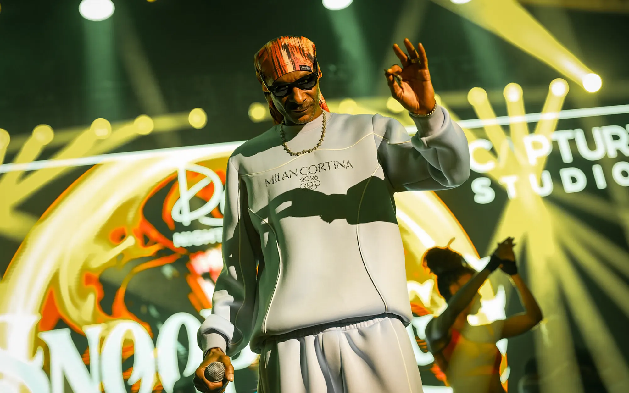 Hand raised mid verse against the stage screens