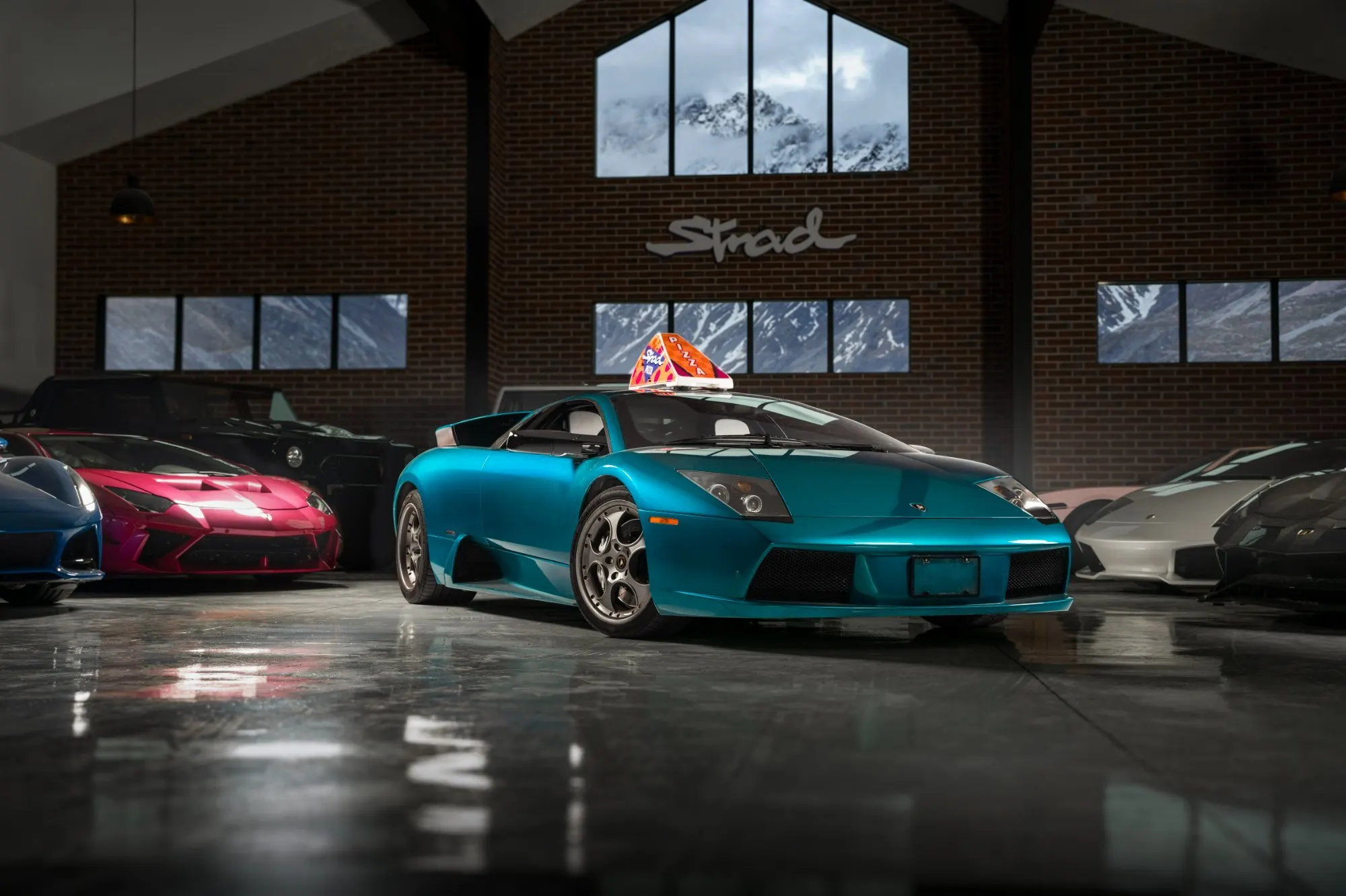 Teal roadster on a showroom floor under the neon sign