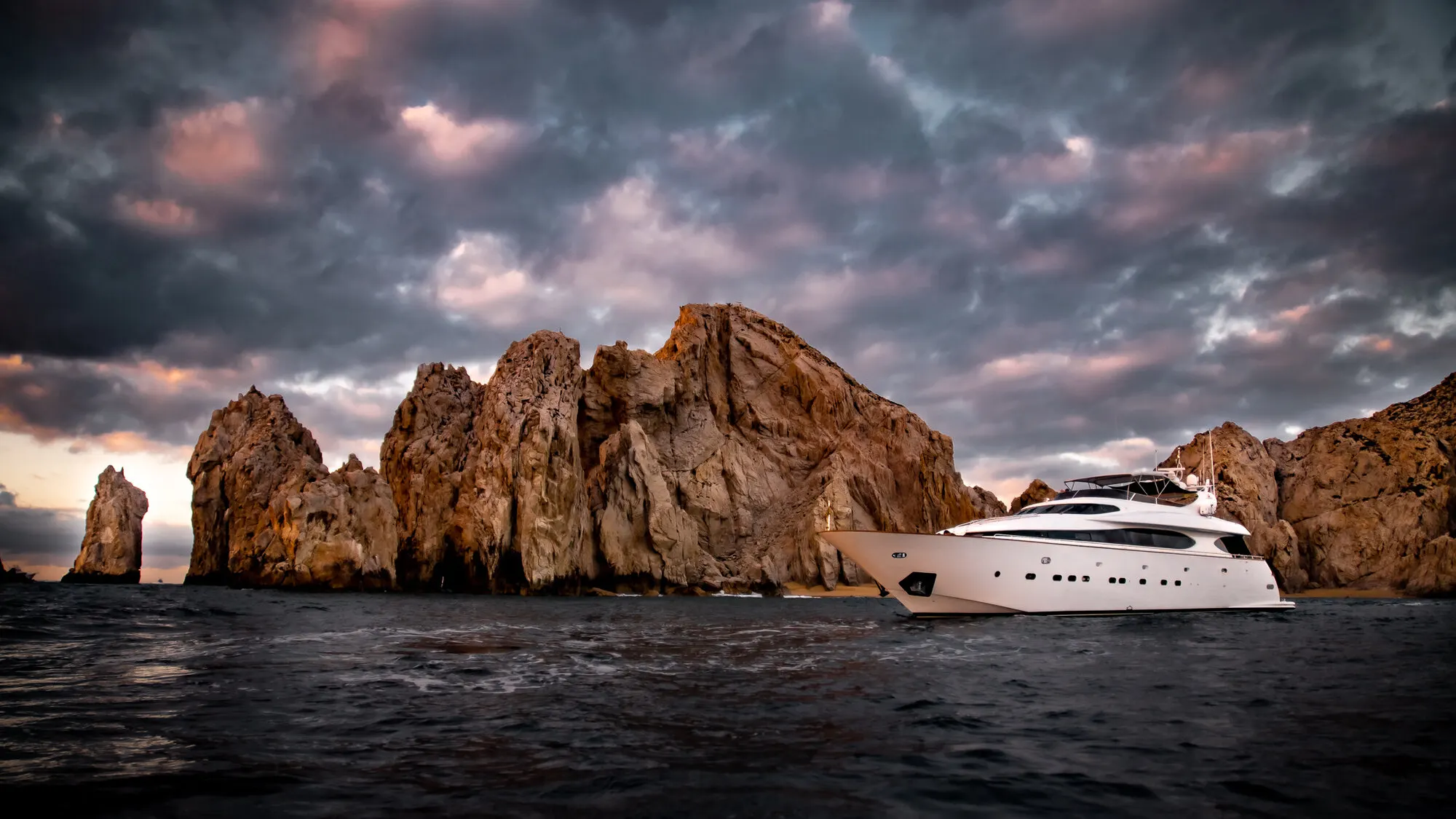 Wide, the yacht small against the rock formations at dusk